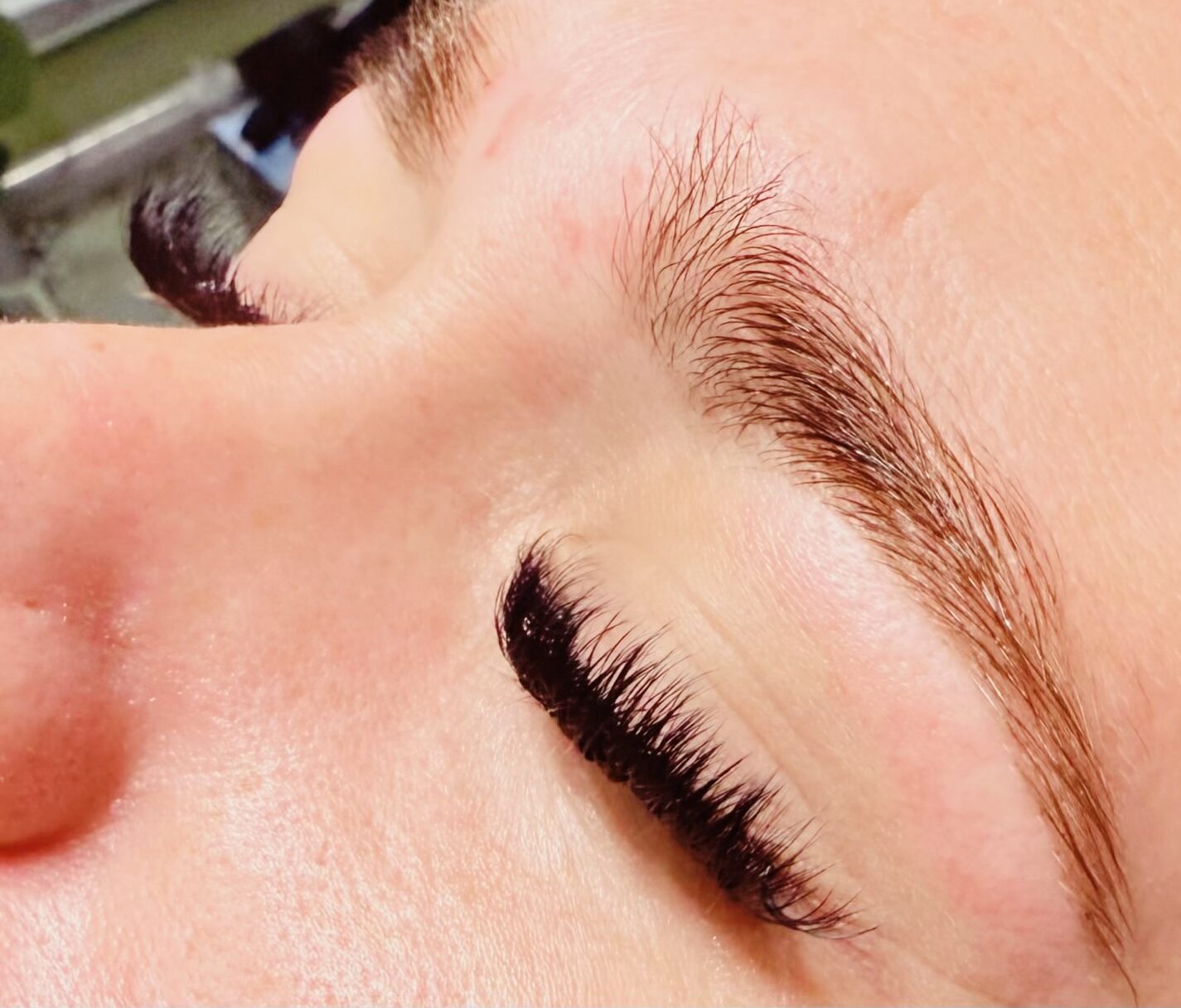 A close up of a customer's eyebrows and eyelashes with closed eyes